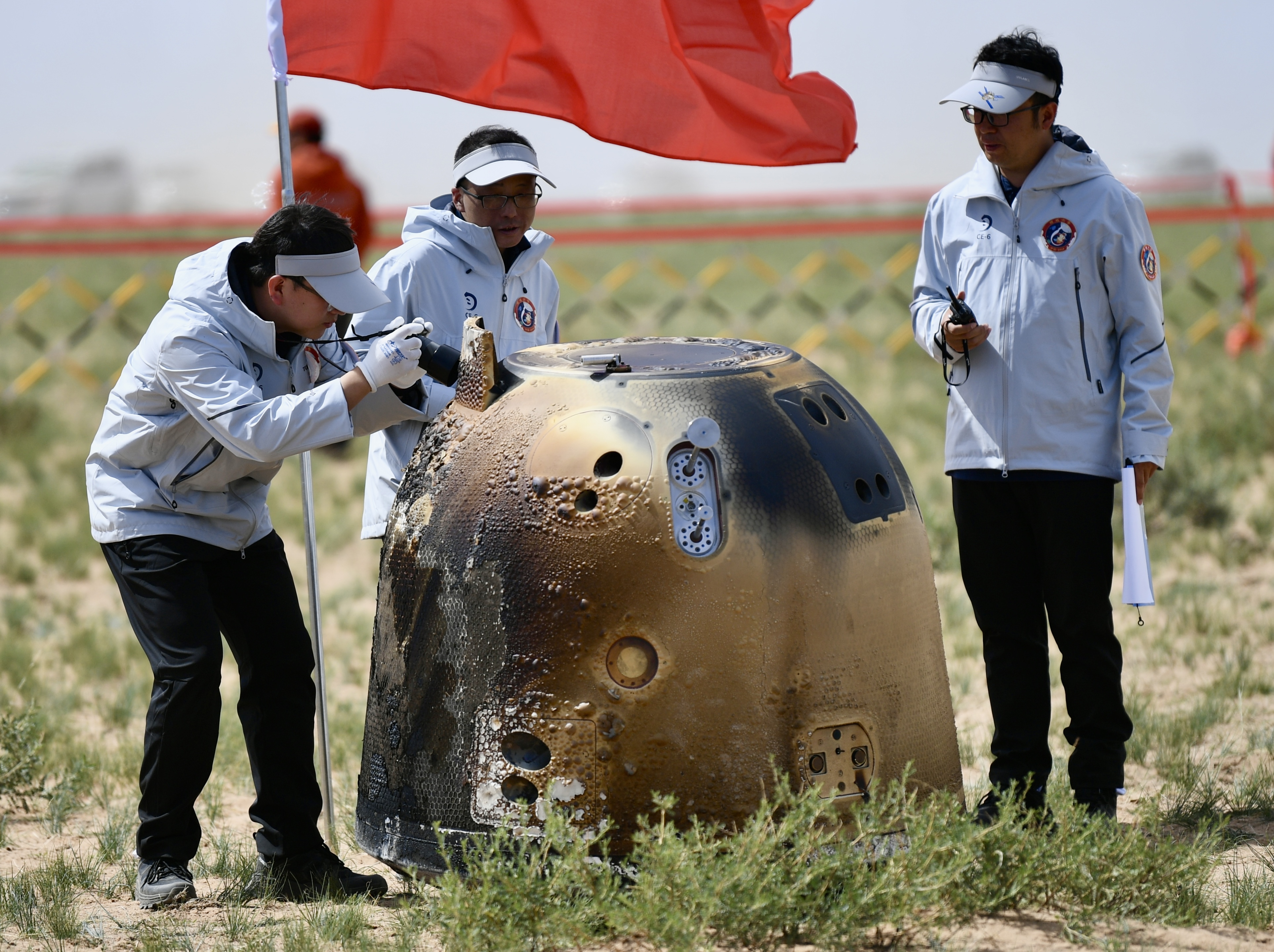 内蒙古当地群众高举国旗,庆祝嫦娥六号返回器安全着陆